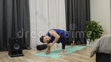 适合在家做运动和健身训练的黑发女郎。女人向前倾，在瑜伽垫上伸展。家庭主妇早上